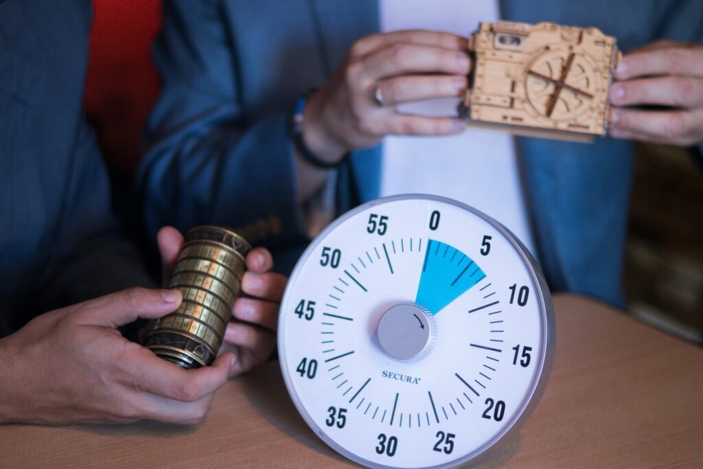 People holding a timer, intricate lock mechanism, and puzzle-themed camera to represent Mystery Mayhem's iconic escape room offerings as of the single most fun things to do near Grove City PA