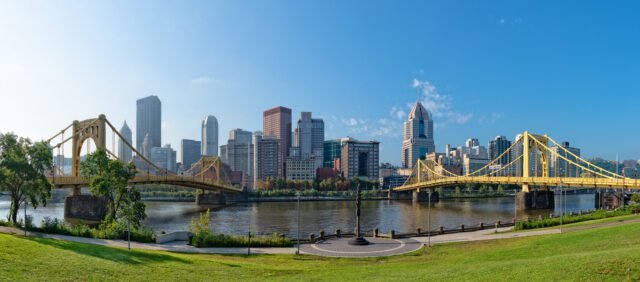 Scenic view of Pittsburgh skyline and yellow bridges over the Allegheny River, a popular spot for group activities in Pittsburgh.