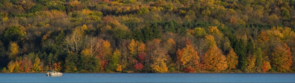 A boat cruising on Lake Arthur surrounded by colorful autumn trees at Moraine State Park.