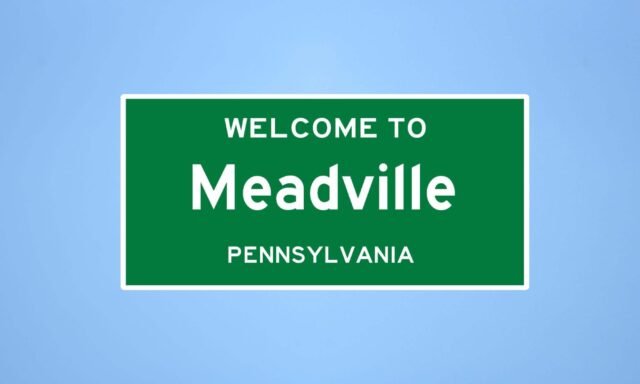 Green road sign for Meadville Pennsylvania welcoming visitors to the area.