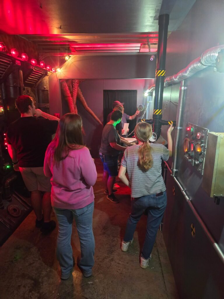 A group of six people collaborating inside a Mystery Mayhem Escape Room.